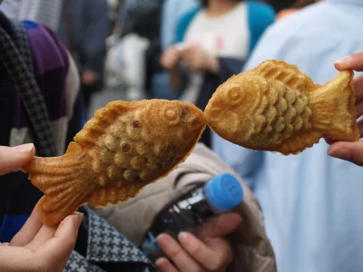 To personer holder opp taiyaki-kaker, som om fiskene kysser