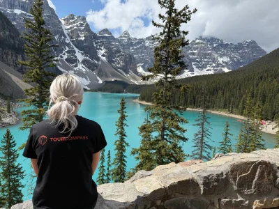 Kvinne i TourCompass-t-skjorte ser utover vannet ved Lake Louise i Canada