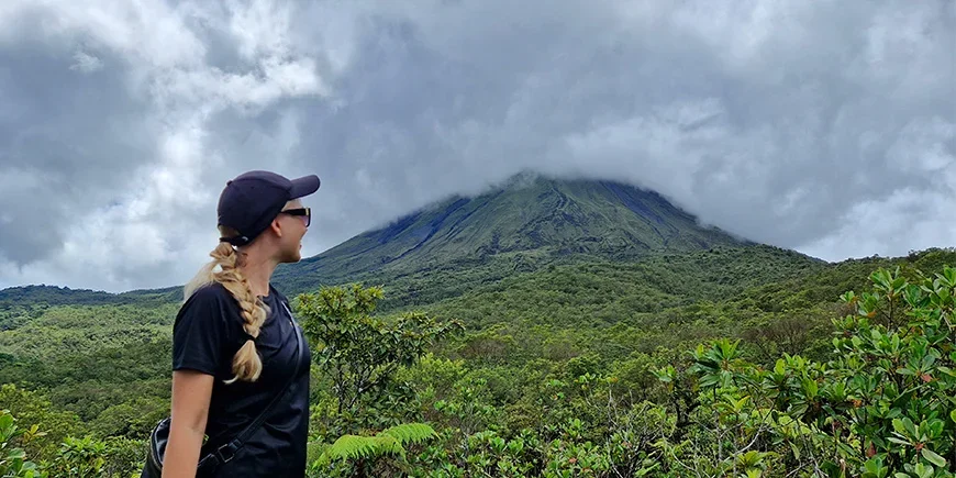 Nadia fra TourCompass foran Arenal-vulkanen på en overskyet dag i Costa Rica