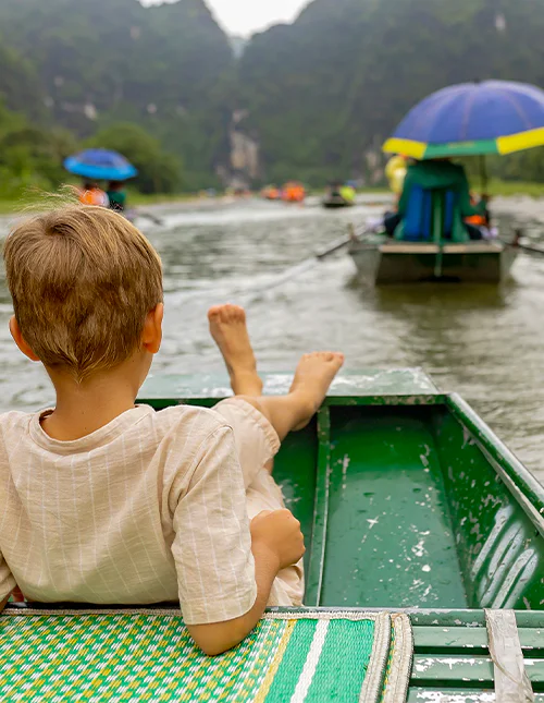 Et barn nyter en båttur i Ninh Binh, Vietnam
