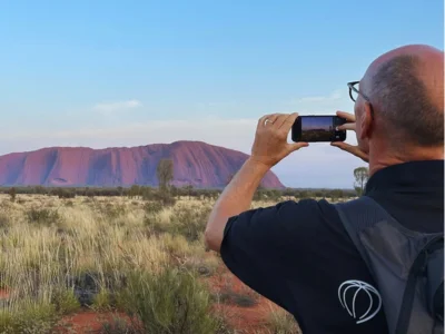 Mann tar bilde med mobiltelefon av Uluru i Australia