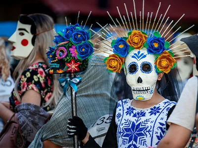 Kvinne utkledd med skjelettansikt og blomster i håret i forbindelse med de dødes dag i Mexico