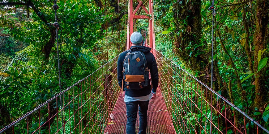 Mann som går alene på en hengebro i Monteverde Cloud Forest i Costa Rica