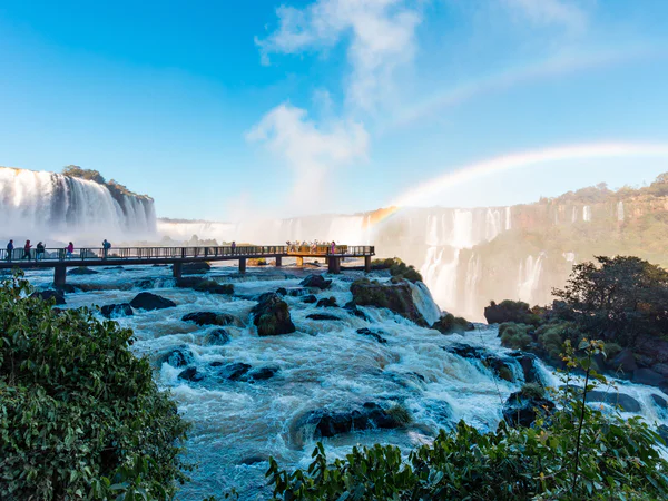 Gangbro på den argentinske siden av Iguazú-fossene på en solrik dag