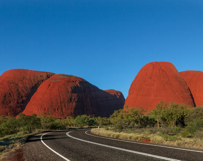 Kata Tjuta i Australia med røde klippeformasjoner og en svingete vei gjennom det grønne ørkenlandskapet