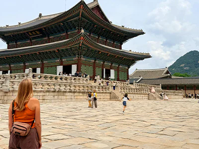 Kvinne står og ser på Gyeongbokgung-palasset i Seoul