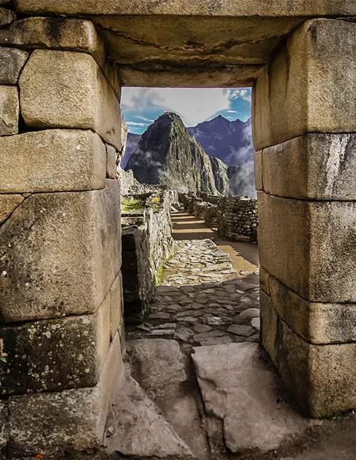 Steinport med utsikt mot Machu Picchu og de tåkekledde Andesfjellene.