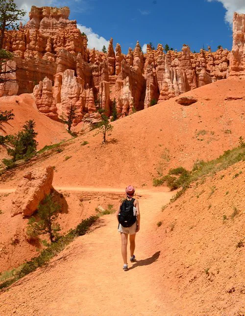 En person går på en sti mellom de ikoniske oransje klippene i Bryce Canyon National Park i Utah, USA.