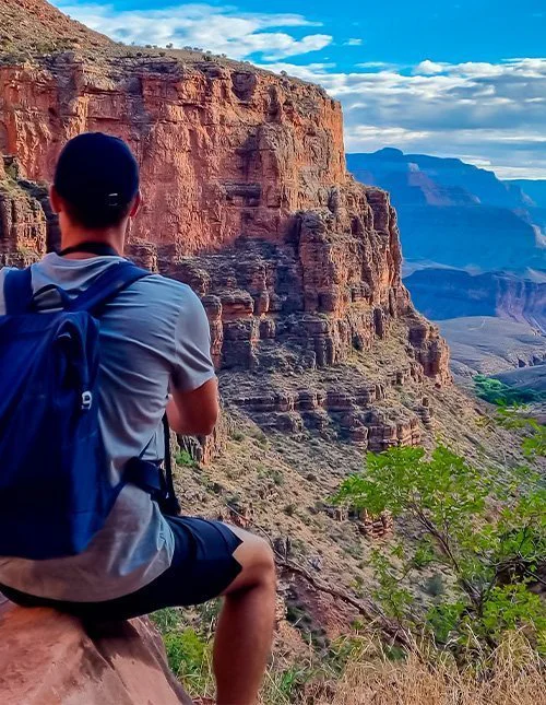 Mann på en klippe langs Bright Angel-stien med utsikt over South Rim i Grand Canyon nasjonalpark