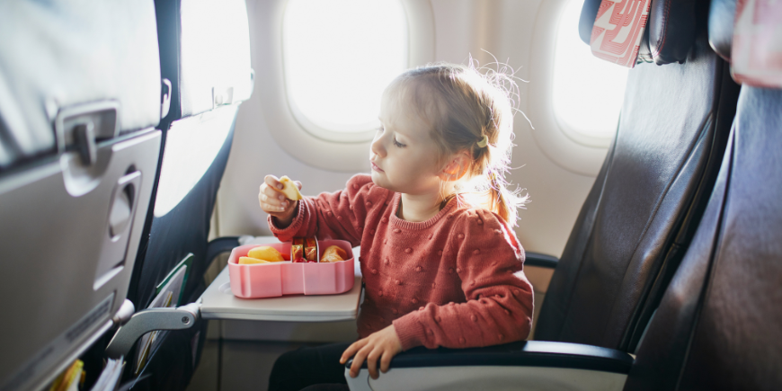 Barn spiser snacks på setet i et fly