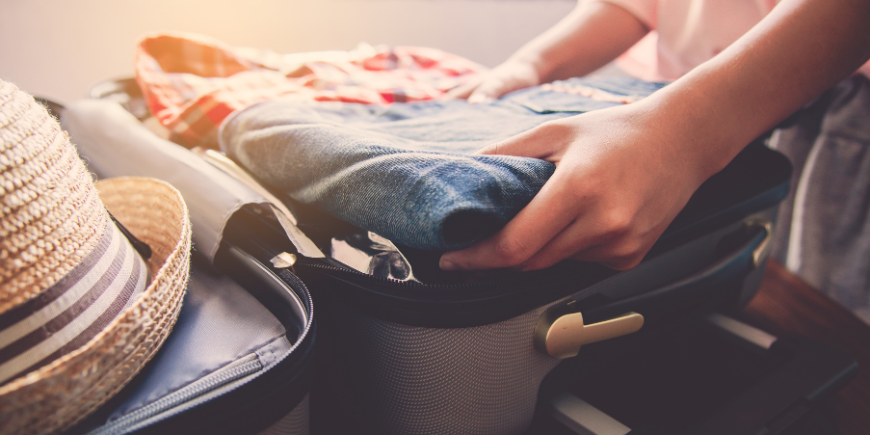 Kvinne pakker reiseklærne sine på soverommet
