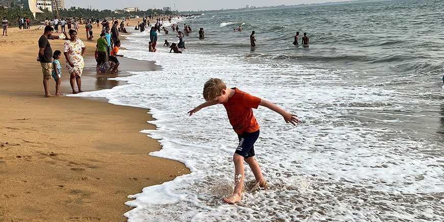 Gutt i vankanten på gylden strand på Sri Lanka
