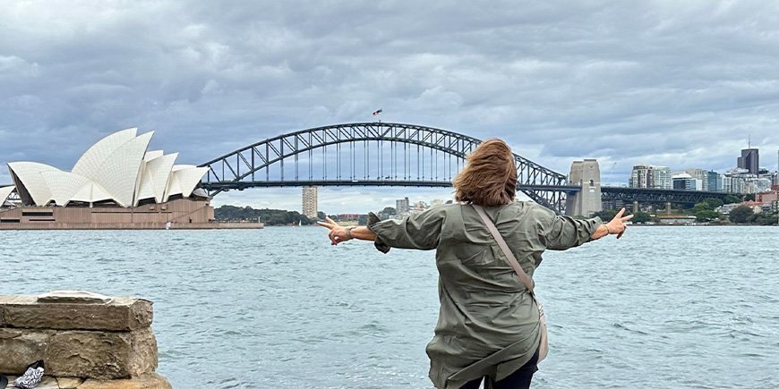 Beate står foran operahuset og Sydney Harbour Bridge i Australia.