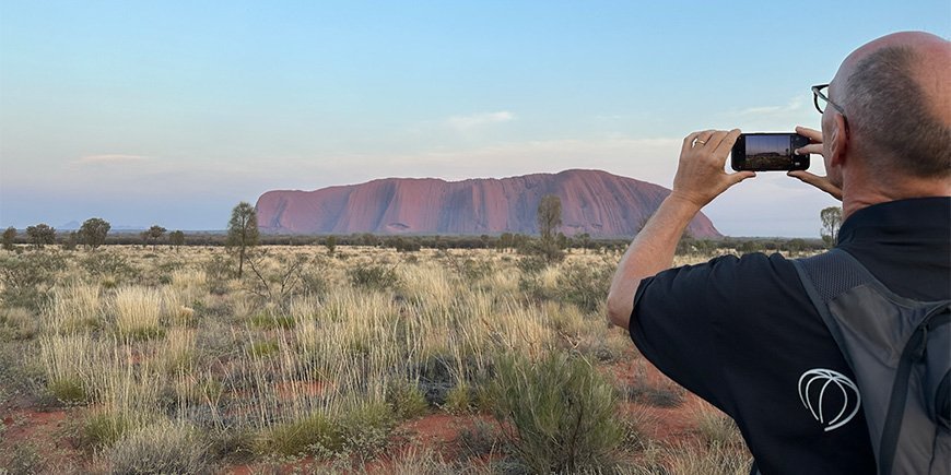 En mann tar et bilde av Uluru i Australia.