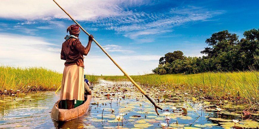 Kvinne seiler i båt i Okavango-deltaet i Botswana
