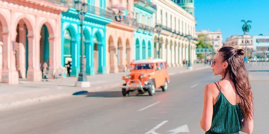 Kvinne går gjennom gatene med fargerike bygninger i Havanna, Cuba
