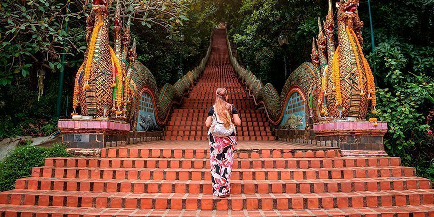 Kvinne klatrer opp trappene ved Doi Suthep-tempelet i Chiang Mai, Thailand.
