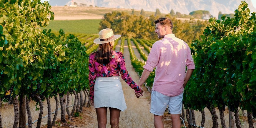 Kvinne og mann holder hender i en vingård i Sør-Afrika