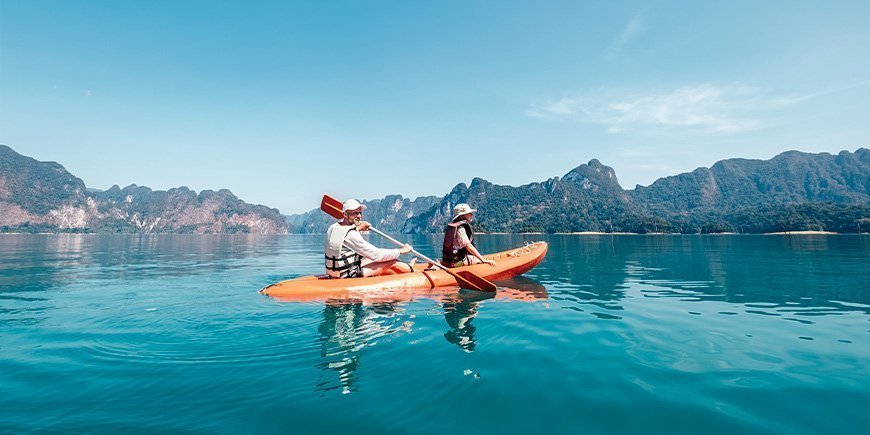 Far og sønn padler kajakk på innsjøen i Khao Sok nasjonalpark