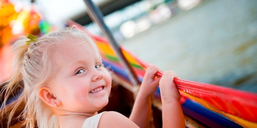 Smilende jente sitter i en båt på elven Chao Praya i Thailand