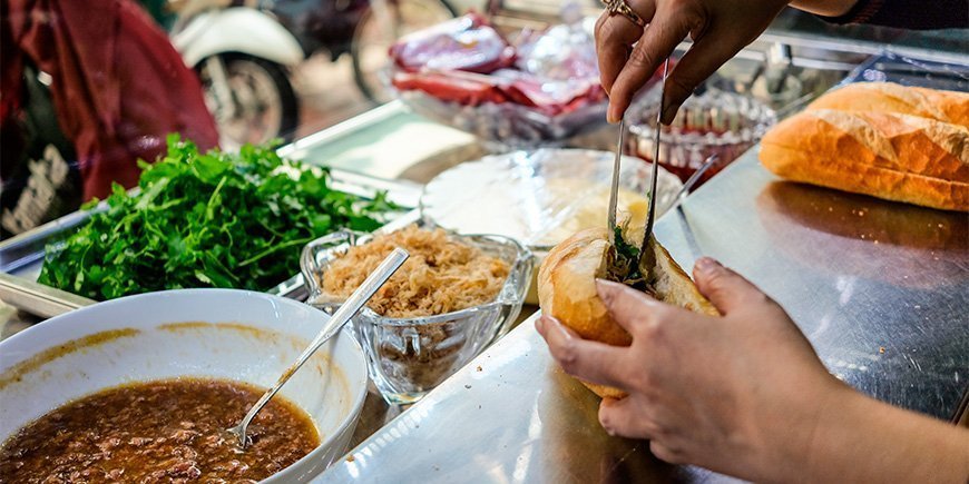 Kvinne lager en Banh Mi sandwich i Ho Chi Minh-byen, Vietnam