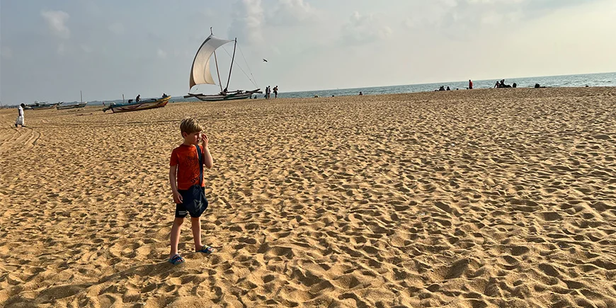 Gutt som står på Negombo-stranden i Sri Lanka