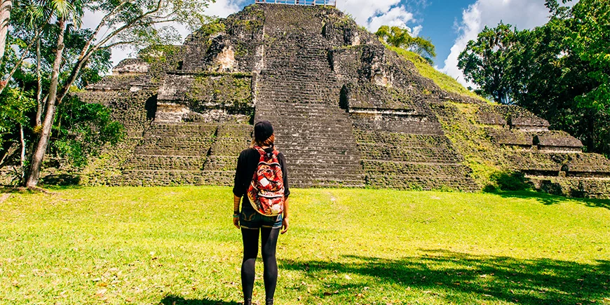 Kvinne foran pyramide i Tikal nasjonalpark 