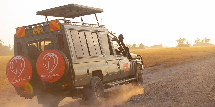 Jeep med TourCompass-logo kjører på savannen i Kenya