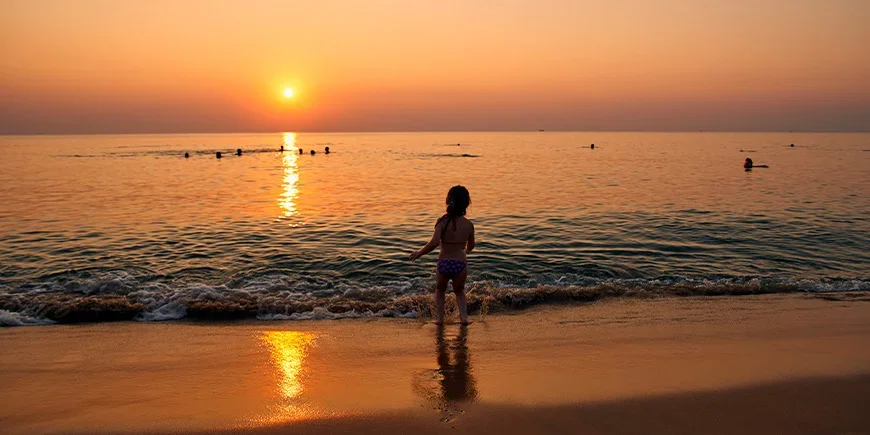 Jente som leker i vannet på Phu Quoc i solnedgangen