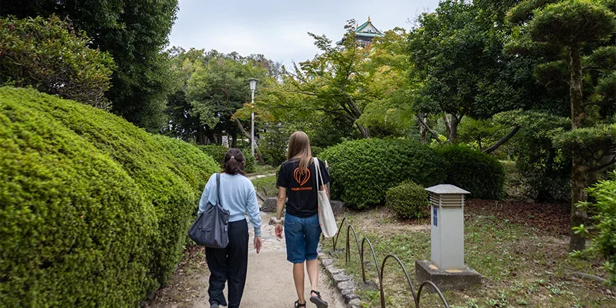Japansk guide går sammen med en TourCompass-ansatt ved Osaka Castle i Japan