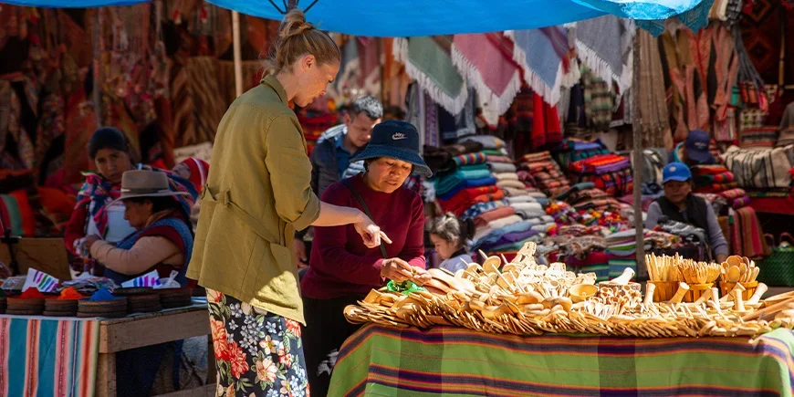 Kvinne snakker med en lokal om varene hun selger på et marked i Cusco i Peru