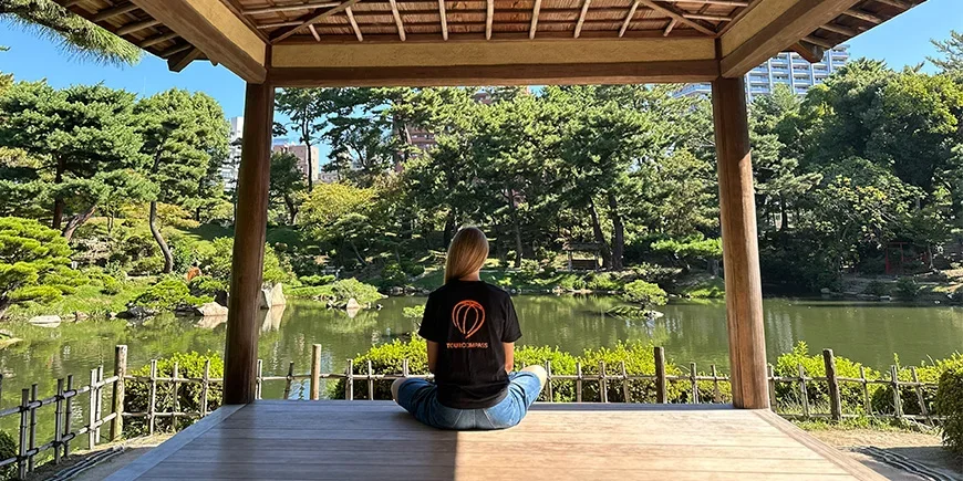 Kvinne i TourCompass-t-skjorte i vakker japansk hage i Hiroshima