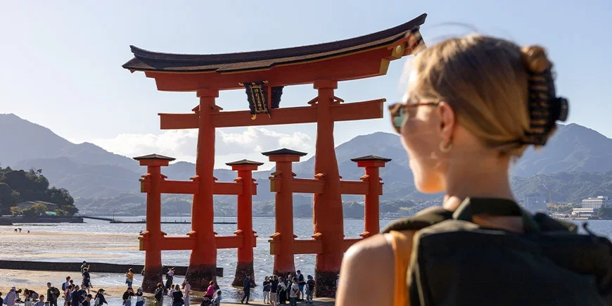 Kvinne ser på det røde tempelet på Miyajima-øya i Hiroshima