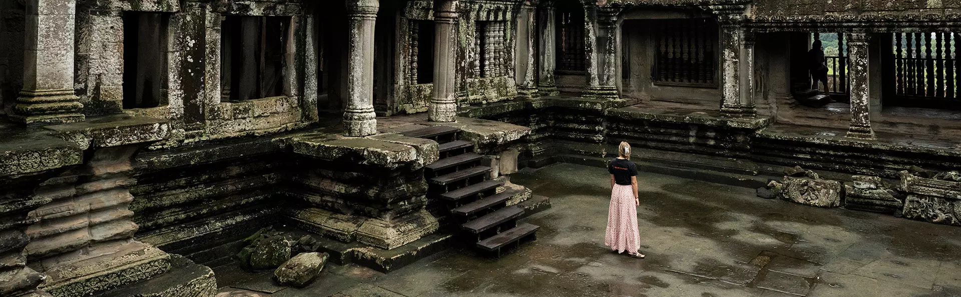 En kvinne i TourCompass-T-skjorte ser på ruinene ved Angkor Wat