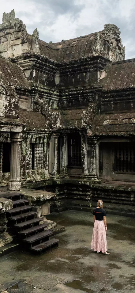 En kvinne i TourCompass-T-skjorte ser på ruinene ved Angkor Wat