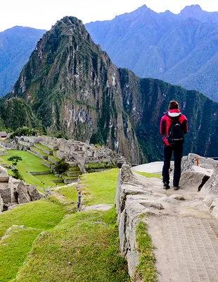 Turist ved ruinbyen Machu Picchu ved soloppgang